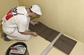 Dlaždice se pokládá na zazubenou plochu a přitlačí se. Postupně se osazuje dlažba po celé ploše s použitím obkladačských křížků, popř. klínků pro zajištění stejné tloušťky spár. U styku stěn je nutné dodržet dostatečné šířky dilatačních spár