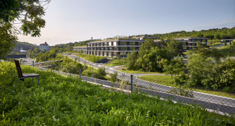 Architekti budovu navrhli tak, aby respektovala prostředí radlického údolí – kopíruje reliéf svahu, díky střešní zeleni splyne s okolím.