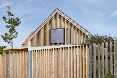 Ve štítech nové sedlové střechy jsou velká okna, která stíní a částečně zakrývají modřínové lamely