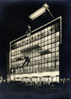 Důležitou součástí efektu fasády bylo i její noční osvětlení. Architekt Kittrich: „Zasklené uliční průčelí 33/18 m prosvětlováno jest 100 kusy výbojek Philora SO 400. U výkladních skříní jest použito smíšeného světla rtuťových výbojek Philora HP 300 a běžných žárovek (dosaženo bělosti denního světla). Vysunutá deska dominanty jest podsvětlována sodíkovými lampami. Večerní osvětlení jest zdůrazněno neonovým osvětlením v rozsahu 1000 m trubic a asi 100 transformátorů.“