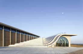 Organický tvar betonového amfiteátru vyjadřuje respekt k vinařskému řemeslu a k jeho tradici a svým elegantním reliéfem chce se svým okolím nenásilně splynout