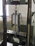 Zdvojené zkušební těleso pro zkoušku podle ČSN EN 12090:2013. Při zkoušce působí zkušební zařízení tlakem na střední kovovou plotnu. Nápad se spřažením krajních ploten závitovými tyčemi významně eliminuje nežádoucí účinky excentricity protisměrných rovnoběžných sil