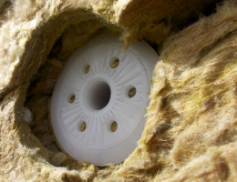 Obr. 6: Plastová kotva pro ETICS ejotherm STR U patří mezi nejlepší výrobky na trhu. Zápustná montáž se u ní provádí pomocí speciálního přípravku, který povrch izolační desky nefrézuje, ale prořezává. Talíř kotvy následně vtlačí naříznutou část desky o tloušťce cca 15 mm do spodních vrstev izolační desky. Na snímku je vidět, jak z důvodu vtlačení zátky, vyříznuté z tuhé povrchové vrstvy, dojde k zahájení procesu lokální separace vrchní tuhé vrstvy od měkčí spodní vrstvy desky