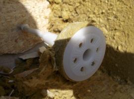 Obr. 7: Plastová kotva ejotherm STR U s vyříznutou tuhou zátkou pod talířem po odstranění měkkých částí dvouvrstvé desky z MW v místě sondy. Vtlačením této tuhé zátky do měkké části desky dojde v místě každé kotvy k lokálnímu rozvrstvení desky. Se zvyšováním počtu takto montovaných kotev se tak paradoxně zvyšuje riziko celoplošné separace vrchní tuhé vrstvy