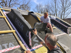 Pokládka fólie a zaizolování pro ostění střešního okna před zateplením střechy. Výhodou fólie DELTA-PVG PLUS je velká odolnost ve smyku, takže se nepoškodí ani při pohybu řemeslníků. Před zateplením funguje zároveň jako pojistná hydroizolace, která chrání pod ní uložené pohledové dřevěné prvky před povětrnostními vlivy