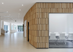 Interiérová stěna z jasanových latí, která vede návštěvníka od vstupu až k velké posluchárně, je odkazem na keramický obklad poslucháren ve starších budovách areálu