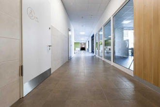 Školní chodby vyžadují odolné podlahy. Zde byla položena dlažba RAKO ze série Extra ve formátu 30 x 30 cm v hnědošedé barvě. Spojovací chodby mezi křídly nabízejí kvalitní vestavěný nábytek s přírodními povrchy