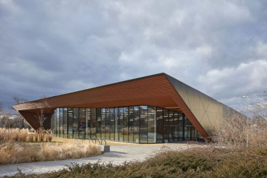 Celá jižní strana plavecké haly má celoprosklenou sloupkopříčkovou fasádu. Zvlněné zasklení zjemňuje ostře řezané tvary obálky