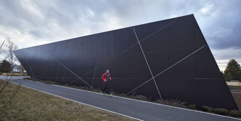 Zateplená provětrávaná fasáda má obklad z černých hliníkových sendvičů. Vzhledem k atypickým kosým tvarům fasád a propsaným liniím z omega profilů se většina desek řezala jako originální tvar