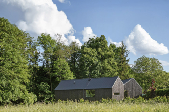 Klienti autory oslovili se stavebním programem bydlení pro čtyřčlennou rodinu s oddělenou částí pro bydlení prarodičů. Dům měl být dřevěný a udržitelný, s nízkými náklady na provoz a s možností aspoň částečné stavby svépomocí.